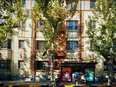 Charming urban street scene with colorful building facade and active bus stop.