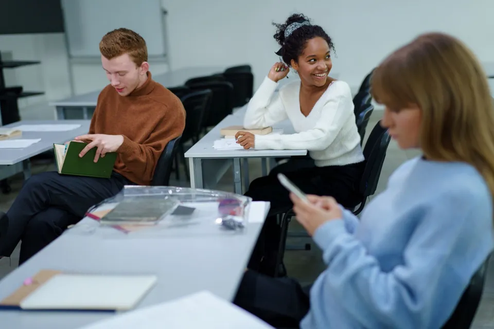 Diverse group of students interacting and studying in a modern classroom environment.