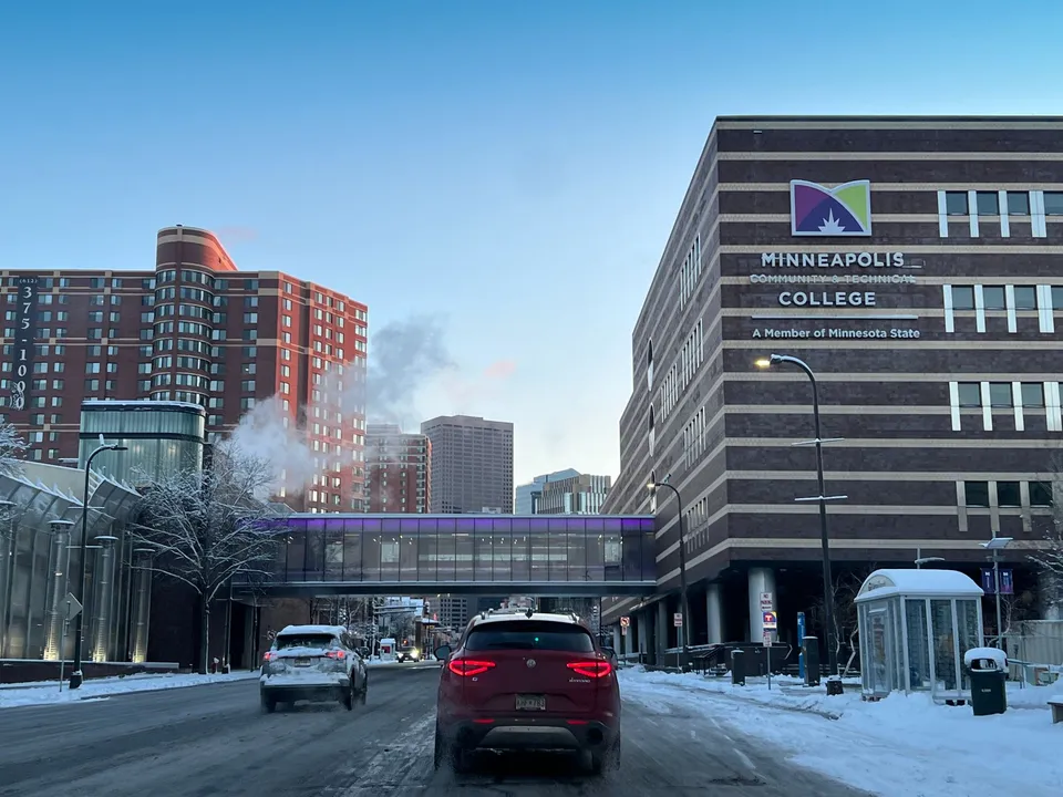 Snowy city street view featuring Minneapolis College and surrounding buildings in winter.
