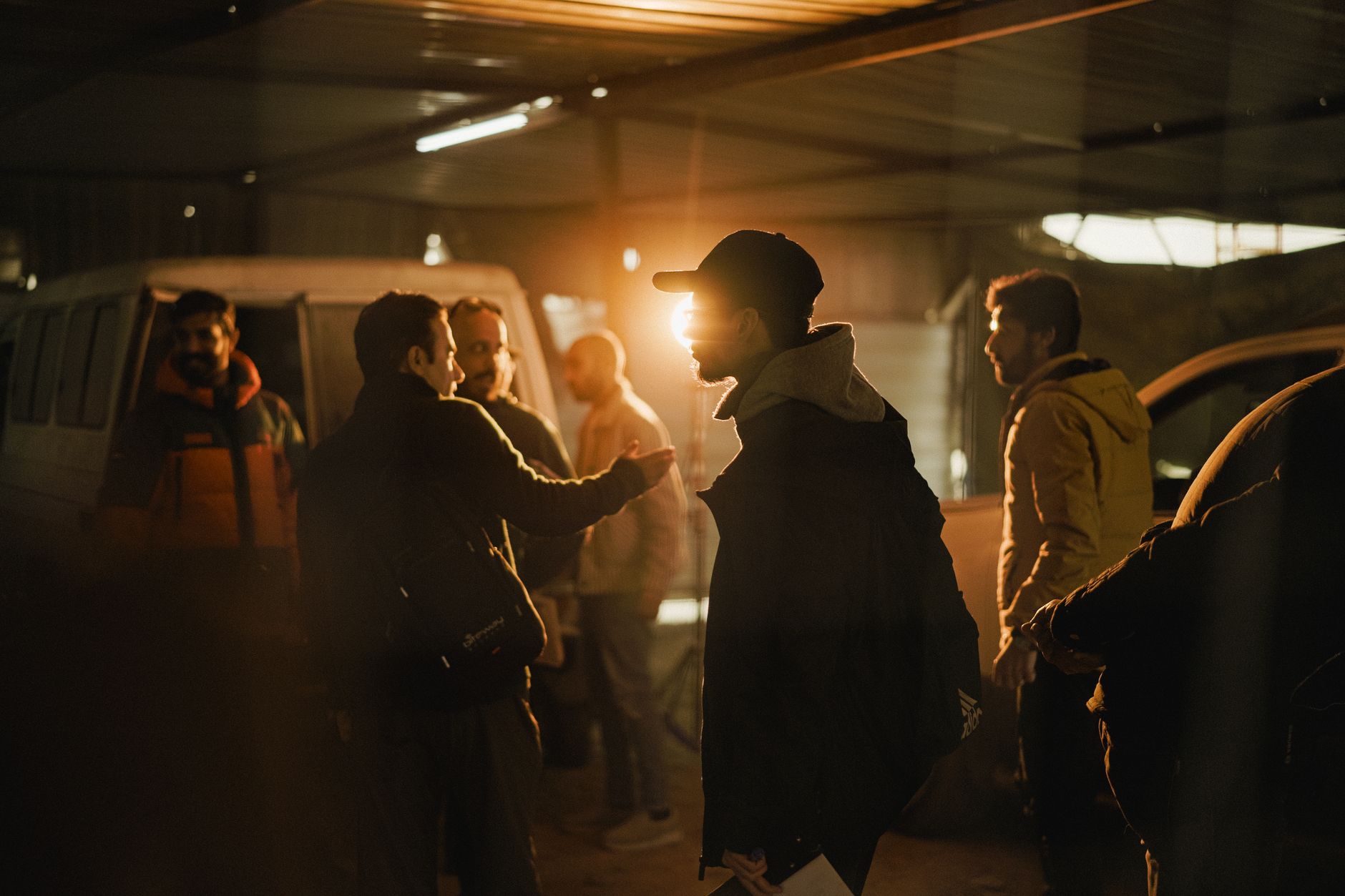 A dramatic silhouette of a group of people standing in a warehouse at sunset.