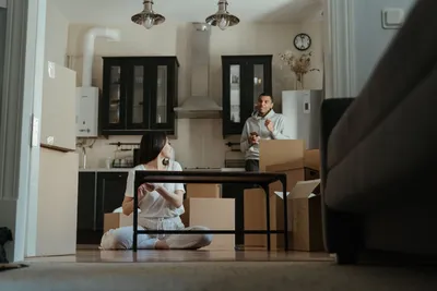 A couple is seen unpacking boxes in their new apartment, setting up their kitchen area.