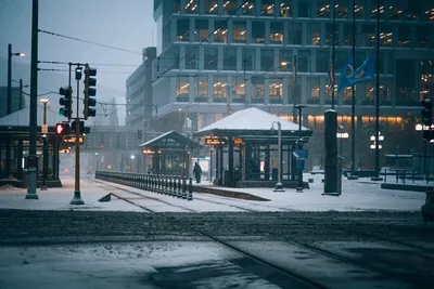 A snowy city street and train station captured in winter evening light.